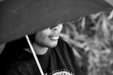 female student with face covered by black umbrella