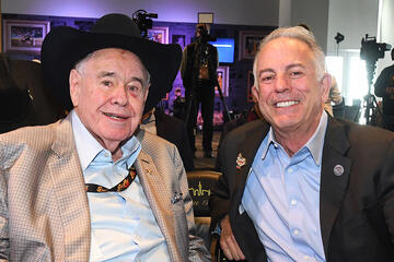 two men posing in suits, one wearing a cowboy hat