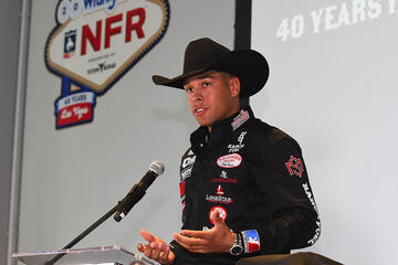 man in cowboy hat talking at microphone under NFR sign