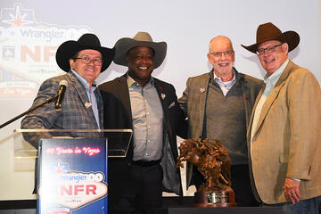 four men posing near podium, three wearing cowboy hats