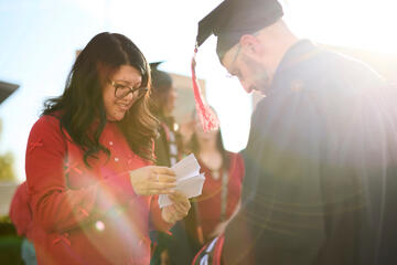 A graduate student receives his name card from UNLV faculty before commencement.