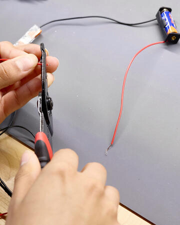 A student cuts a wire connected to a battery.