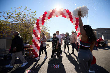 red and white balloon arch with fake snow floating around it