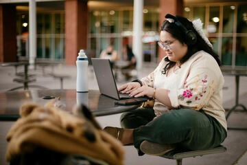Faith Saguisag works on a laptop at an outdoor table