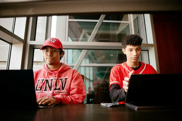 students wearing unlv gear looking at their laptops