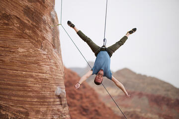 Tony Ferrar hanging upside down while rock climbing