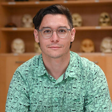 man in glasses posing in from of an anthropology display