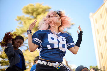 student with pink hair dances in blue shirt