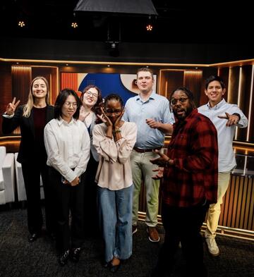 students posing for a photo in front of a broadcast area