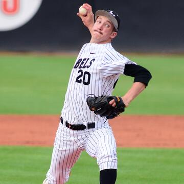White male baseball pitcher in a black and white pinstripe Rebels uniform with the No. 20 and a black baseball cap grips a baseball in his right hand and prepares to deliver a pitch