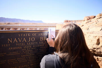 student writing field notes in front of plaque