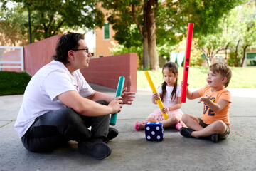 a male UNLV student uses foam instruments and a die to play with preschoolers