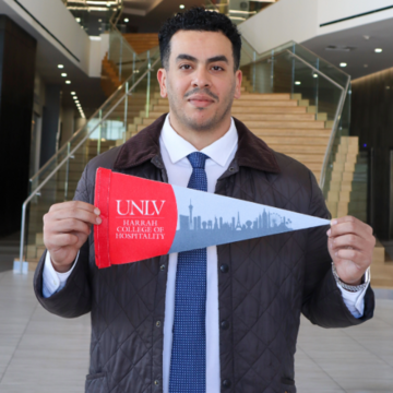 student holding hospitality flag in front of staircase