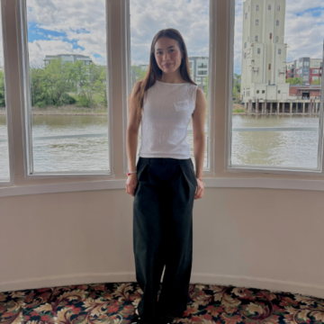 student in front of windows with body of water in the background