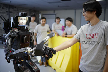 UNLV Engineering team's robot shaking hands with student