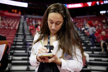Teneka Ash takes notes during a broadcast show at a basketball game.