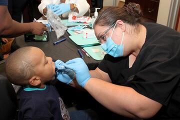 dental student performing procedure on young child