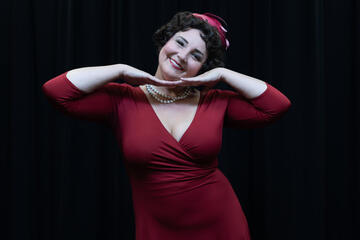 upper half of woman in red dress with hands under chin doing cute pose