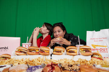 two people eating and surrounded by various fast food items