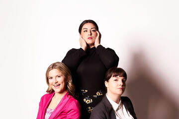 three individuals pose in front of white background
