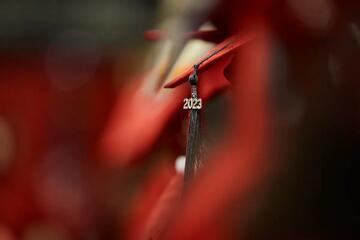 Amid a sea of red graduation caps, a 2023 tassel stands out in the crowd
