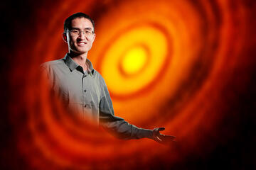 man pictured with ALMA image of the young star HL Tau and its protoplanetary disk