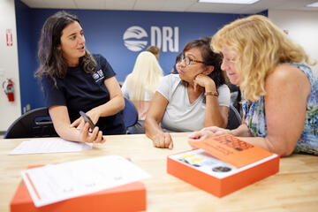 three women discussing a project at a work table