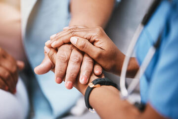 Healthcare practitioner holding a patient's hands