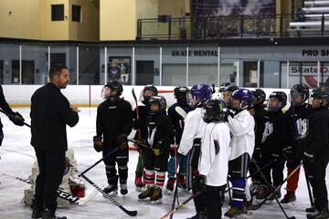 Hockey coach talks to child campers.