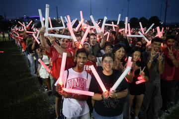 Students hold up light sticks in the shape of L and V at an event