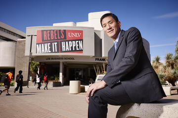 Eric Chiang sits in front of Lee Business School building