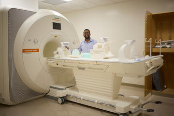 Ayan Sengupta stands next to MRI machine