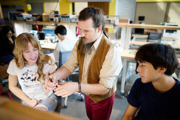 A professor shows two students a prototype.