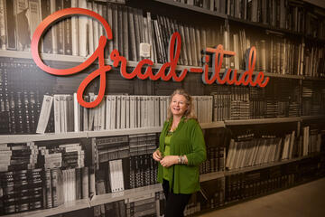Joanna Jezierska in front of a book mural that reads &quot;grad-itude&quot;