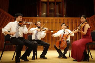 four musicians playing string instruments on stage
