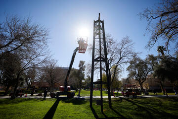 man in cherry picker adjusts hands of clock tower