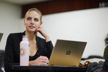 female student in business attire using computer in class