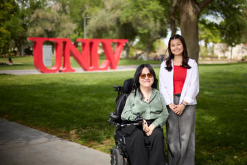 UNLV undergraduates pose for photo outdoors in front of red UNLV letters