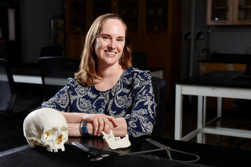 Jennifer Byrnes sits at desk with skull on it
