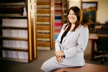 Riana Durrett sits on desk in library