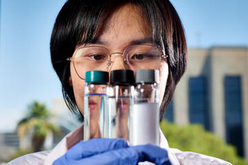 engineering professor Eakalak Khan holds up three tubes of water