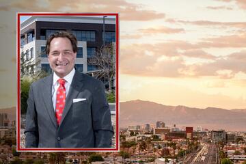 White man with brown hair, gray suit, white collard shirt and red UNLV-logoed tie with a white pocket square smiles as he poses in front of a building, with the photo inset on a stock image that depicts the Las Vegas skyline in the foreground and a mountain range in the background