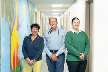 Melba Borrero, Dr. David Di John, and Aaryana Mostafaeipour posing in a clinic hallway.