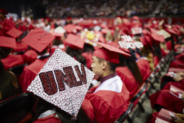 Decorated UNLV mortarboard with students in background