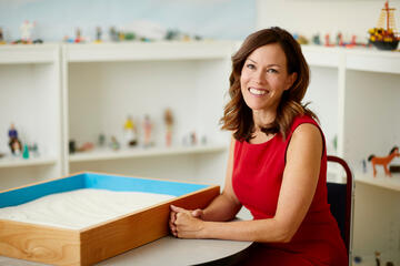 Michelle Paul on a table in a children's playroom