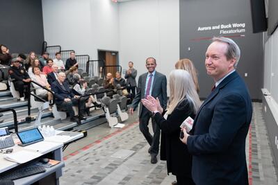 An inductee stands at the front of the auditorium and faces the audience as he accepts his award
