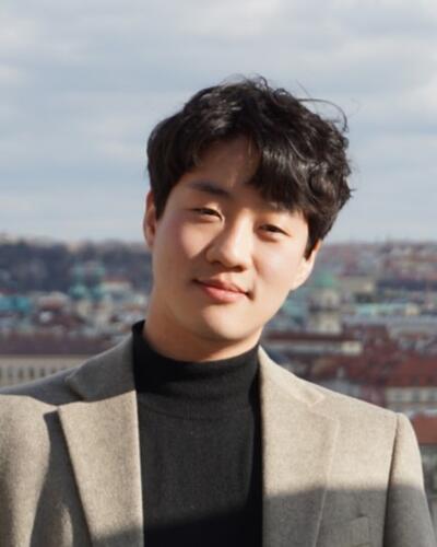 Portrait of WooHyun Jung with a city skyline in the background