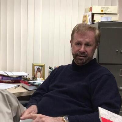 man in dark sweater sitting at a desk