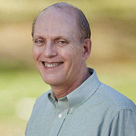 A smiling man wearing a light green dress shirt.