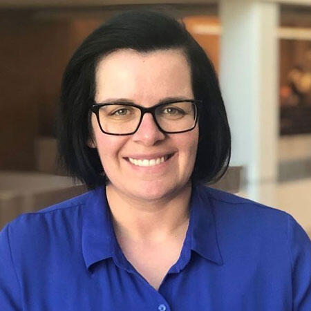 A woman smiling in a blue polo shirt.